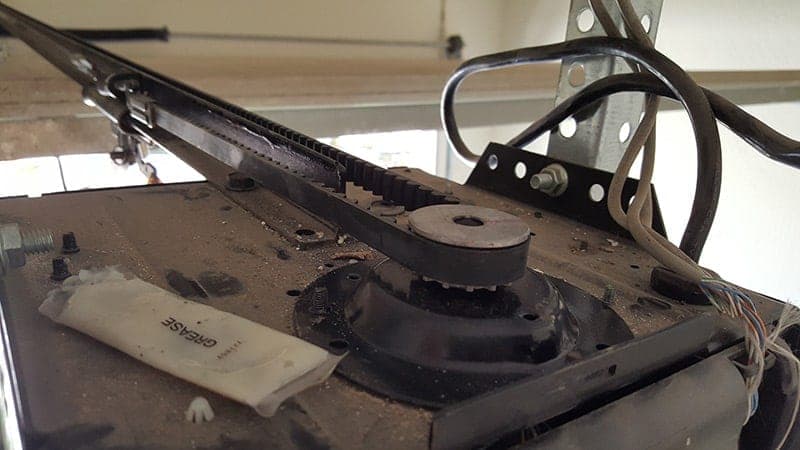 Close-up of a garage door opener belt and drive gear during a repair