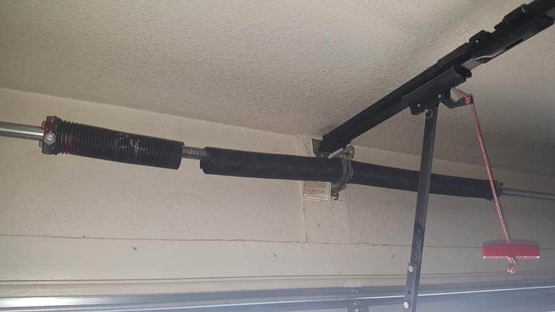 Broken torsion spring with a visible gap above a garage door