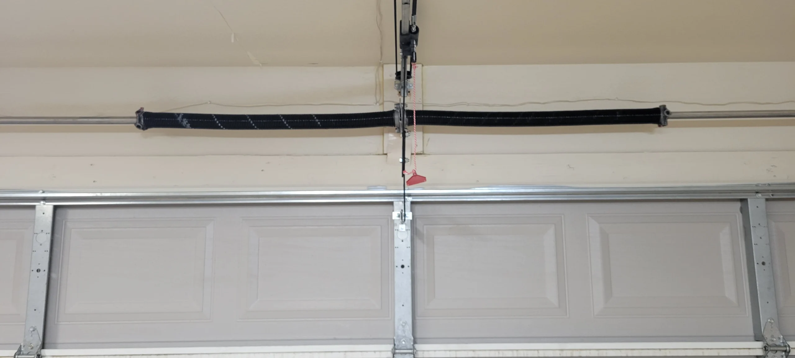 An overhead garage door system showcasing the red emergency cord used for a Garage Door Manual Release