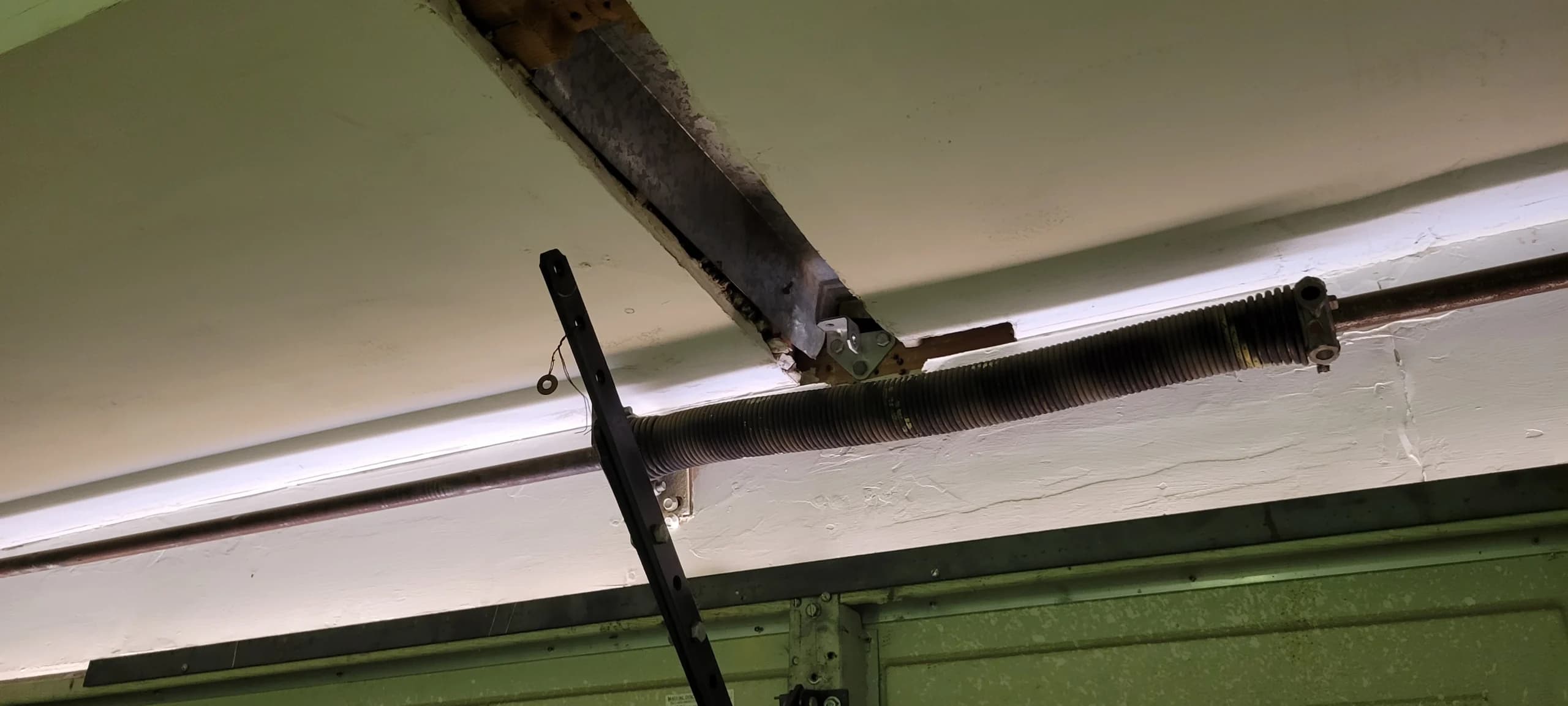 An overhead view of a worn garage spring system, identifying a common cause of garage door torsion spring failure