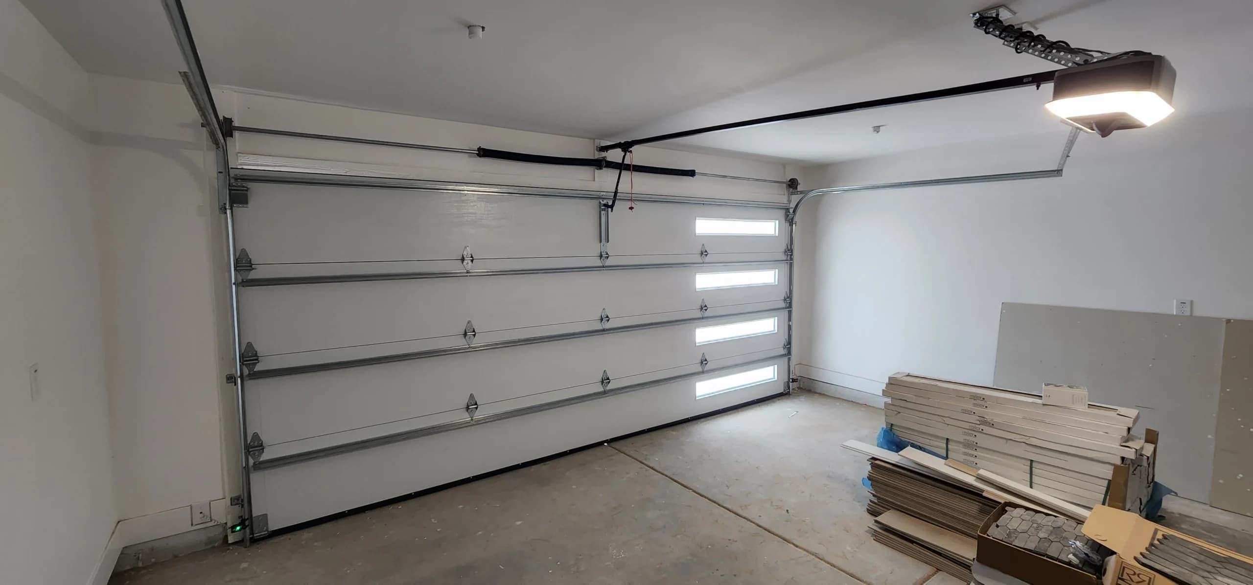 An interior view of a white sectional door with modern side windows installed during a local garage door replacement