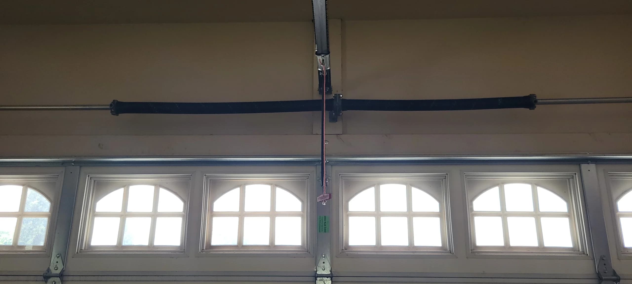 An overhead garage door setup featuring a red emergency release handle used to Manually Open a Garage Door