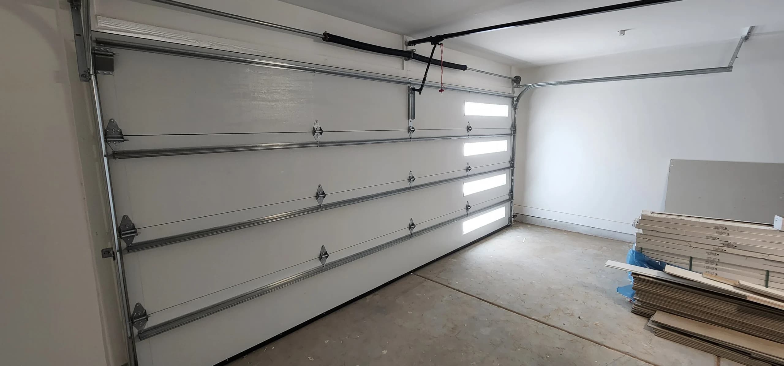 An interior view of a securely installed white sectional door, emphasizing proper maintenance for protecting your garage door