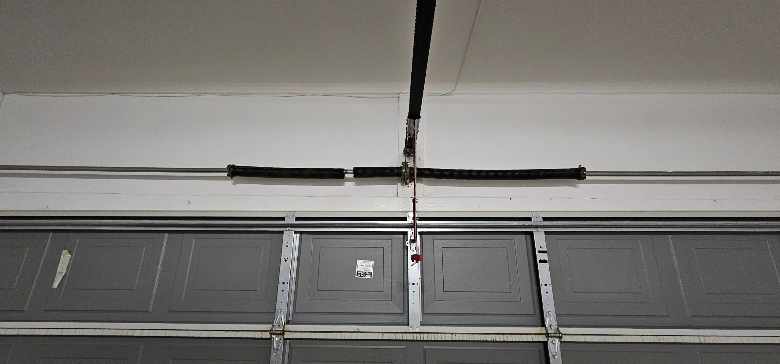 An overhead garage door assembly with an emergency cord,