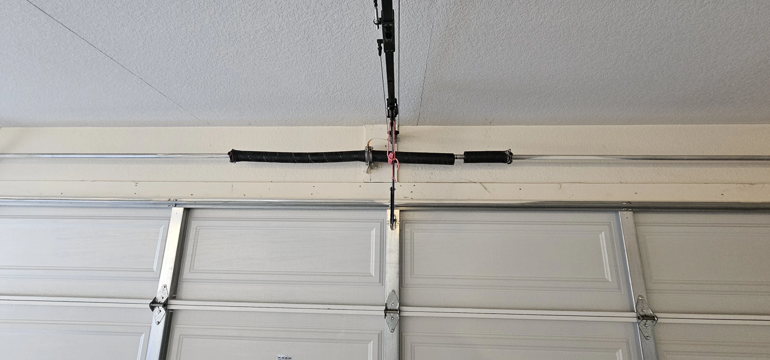 An overhead garage door assembly with a red emergency cord, illustrating Manual Release Safety Tips