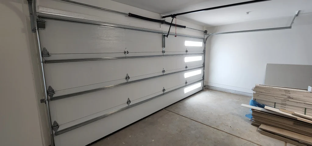 An interior view of a properly aligned white sectional door, highlighting routine inspections to prevent the need for garage door repairs