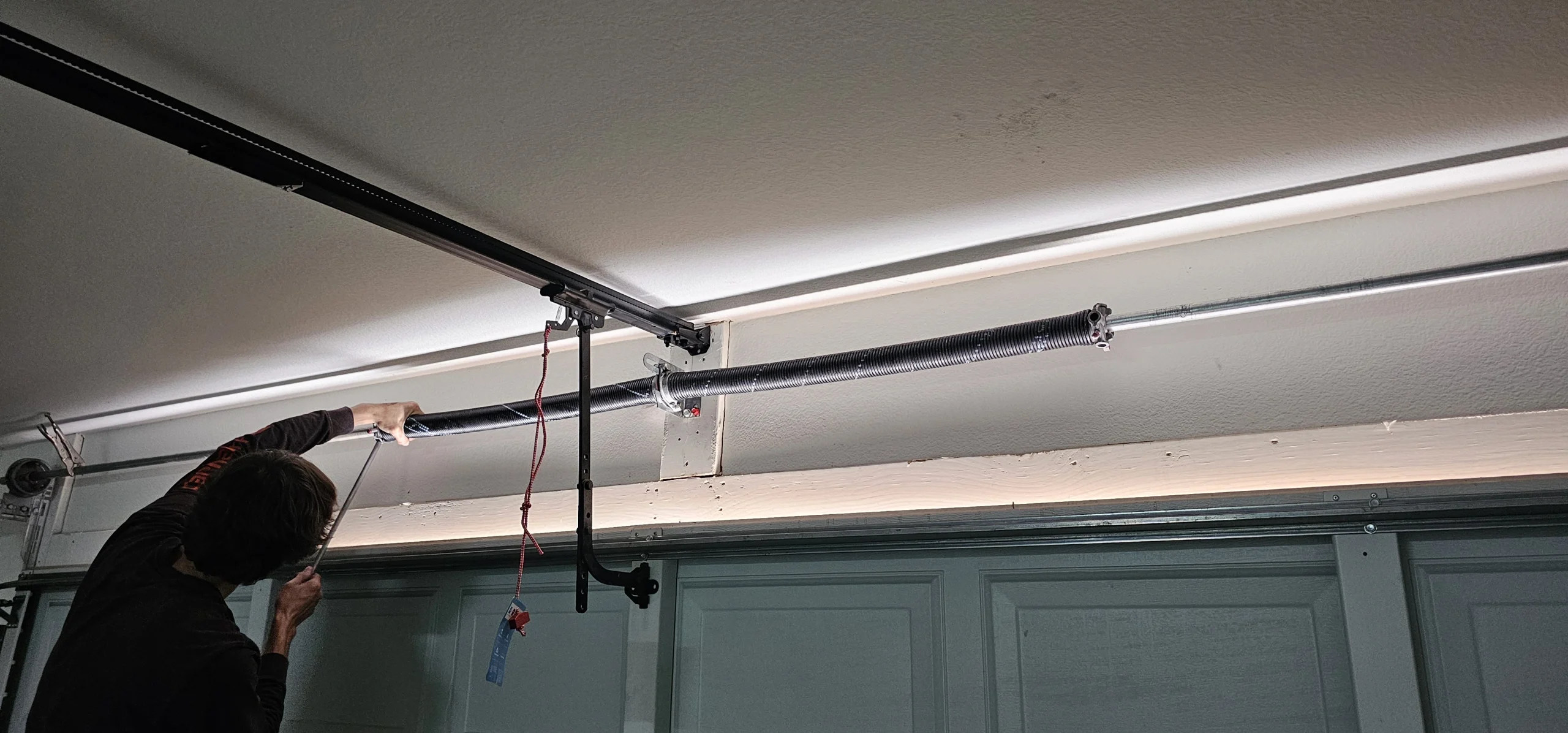 A technician adjusting an overhead garage door system, demonstrating a Professional Spring Service