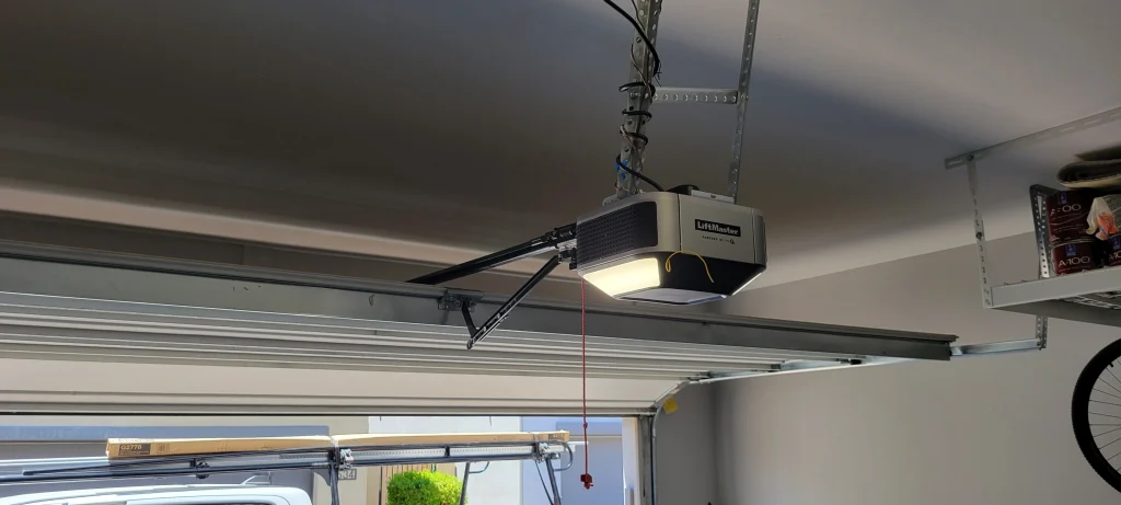 A ceiling-mounted LiftMaster garage door opener with its light turned on, offering a clear visual context for useful tips for adjusting a LiftMaster garage door opener