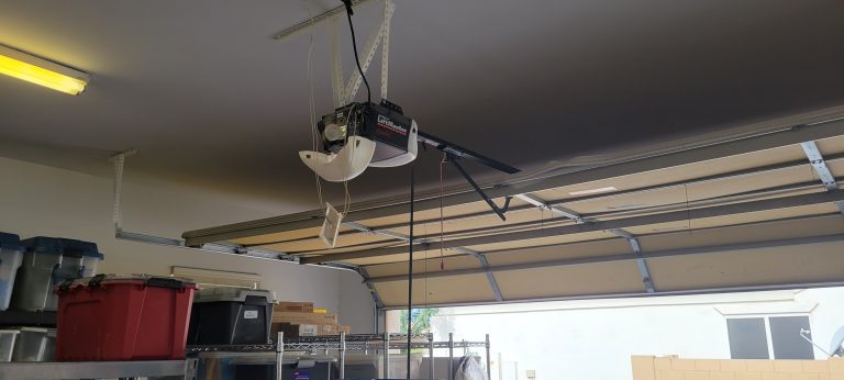 Blog 18 A ceiling-mounted LiftMaster garage door opener with an open light cover in a garage.