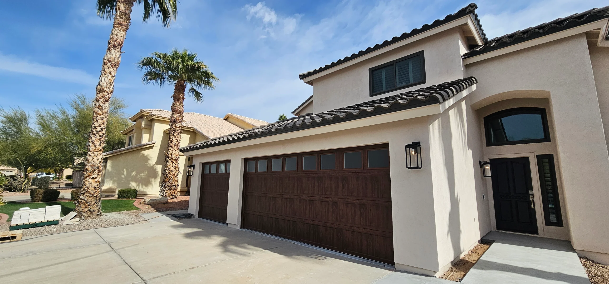Two dark wood grain sectional garage doors with frosted top windows, showing a premium aesthetic improvement from a wooden garage door panel upgrade